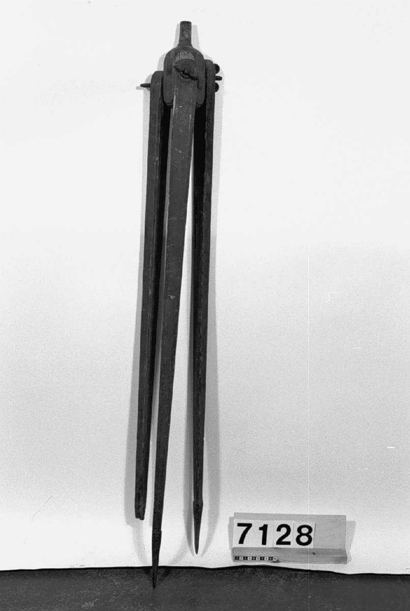 Stativ av trä med beslag av mässing. Text på föremålet "74,403. Dannemora", skrivet med bläck. Stativet: längd: 1430 mm, vikt: 2.4 kg.