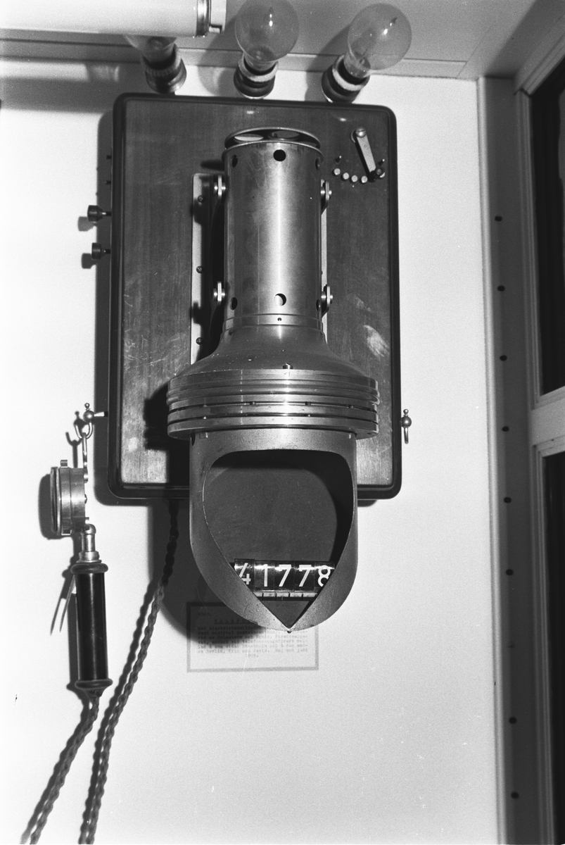 Telefonapparat, väggmodell, med starkströmsmikrofon, konstruerad av Egnér - Holmström. Hörtelefon märkt: 903 Försöksmodell. Märkt: " Aktiebolaget Monofon Stockholm".