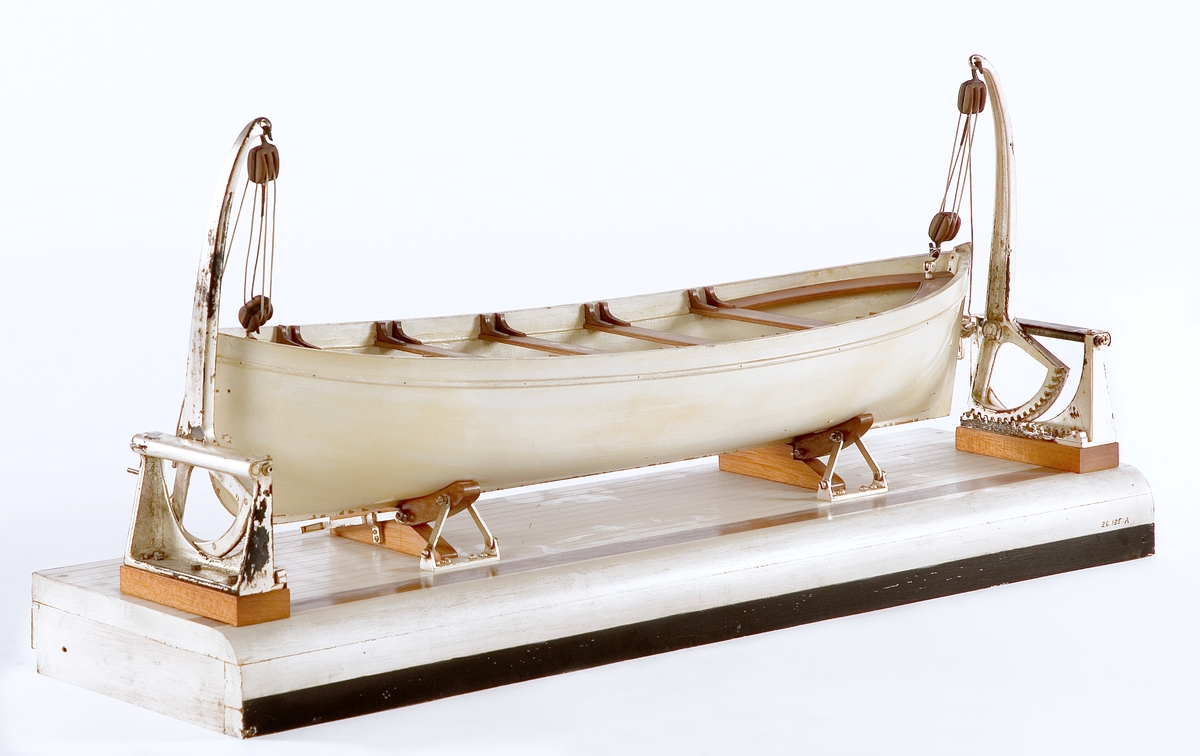 A) Modell av däcksektion med en livbåt och 2 dävertar av Welins patent.