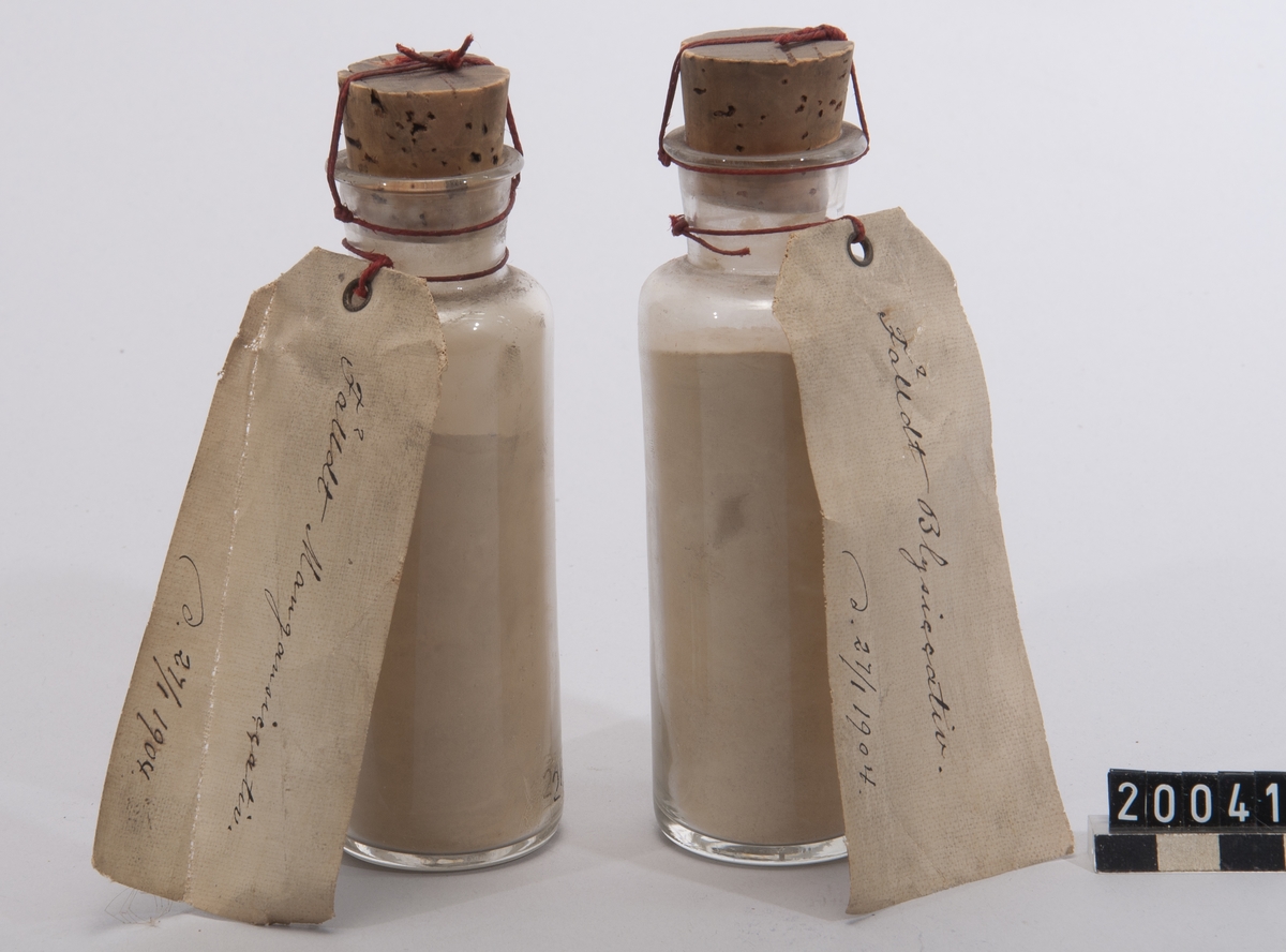 Två prov på siccativ, bly- och mangansiccativ, i burkar av glas med etiketter: "Fälldt Blysiccativ, d. 27/1 1904" samt "Fälldt Mangansiccativ, d. 27/1 1904".