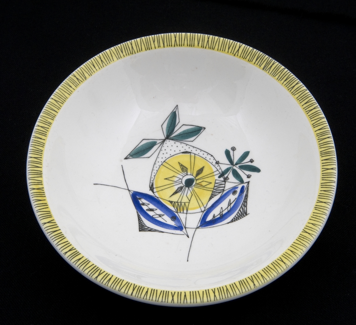 Dekorert med motiv av gul sitron, grønne blader og blå fisker. Kranset med bambusmotiv av svarte streker på gul bakgrunn.
