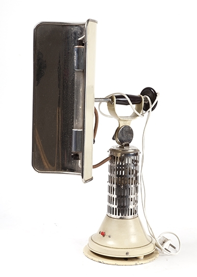 Solariumslampe for hjemmebruk- "høyfjellsol". Rund fot, lang, smal skjerm rundt lysrør. Antatt produsert i 1930-årene, tysk prod. Lakkert, forkrommet. Nettkabel.