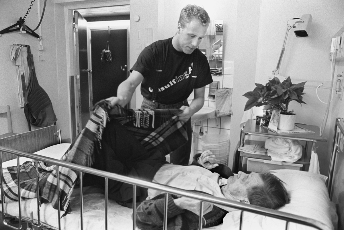 Äldre man får hjälp med en filt, Tunåsens sjukhem, Uppsala 1992