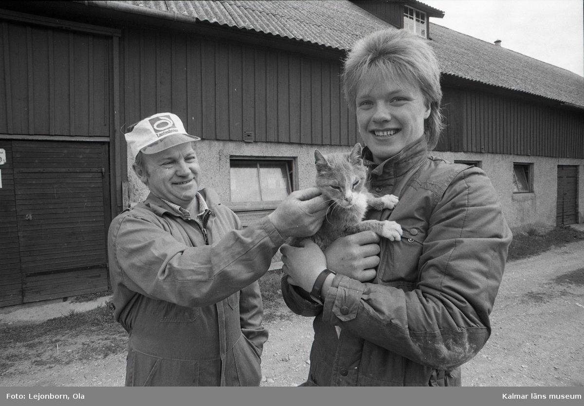 Lantbrukare Svante Svensson och yrkespraktikanten Anders Karlsson med den 25 år gamla katten Sofi.