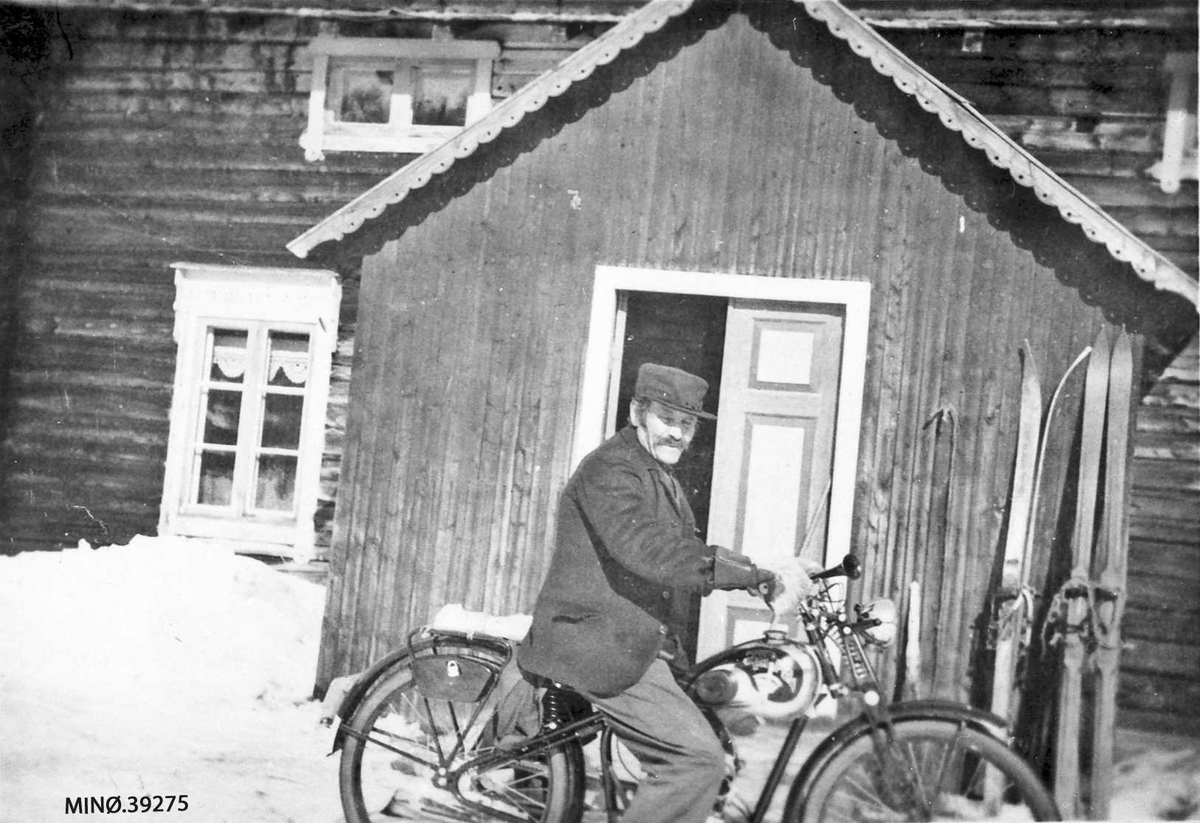Mann på motorsykkel foran bolighus.