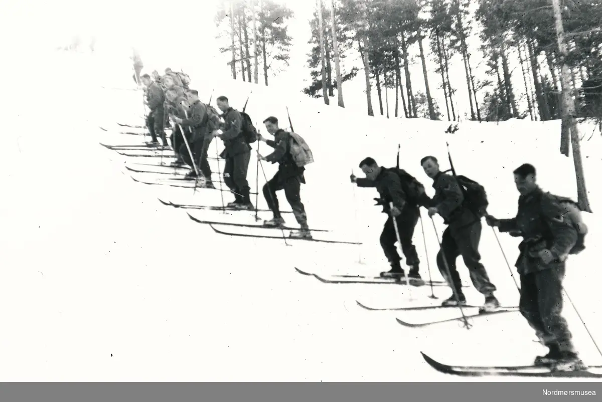 Soldater med ski på vei sidelengs oppover en bratt bakke.