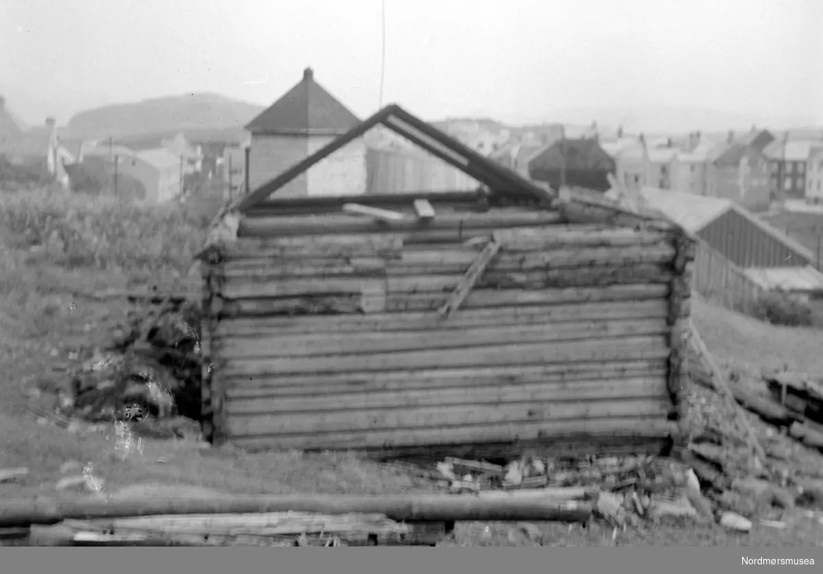 Almskårstua rives i Clausenengen, og taksperrene med nederdelen av stua står igjen. I bakgrunnen ser vi Vardetårnet. Bildet er datert 11. juni 1958. Serie. Nordmøre Museum