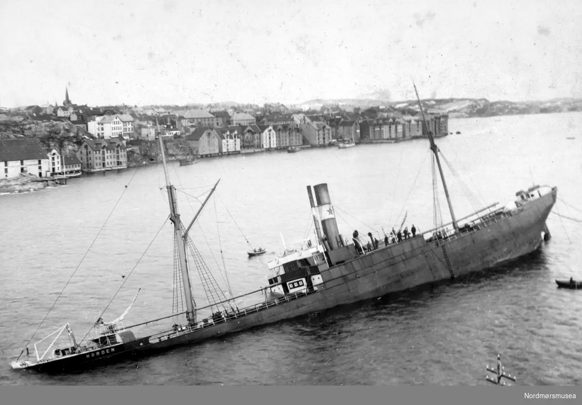 Postkort. ";Nordens"; havari i Sørsundet ved Lervika på Innlandet. 12.02.1903. ";Norden"; som kom til Kristiansund med en saltlast, losset restpartiet på Hammervoldbrygga i Sørsundet. Ved avgangen var det stormbyger fra Nordvest så skipet greide ikke å avansere men drev ned mot sørspissen av Innlandet. Rutebåten ";Nordmøre"; forsøkte å assistere, men greide det ikke. ";Norden"; gikk på grunn med akterenden på Lervikskjæret på Innandet, og sank. Den ble provisorisk tettet og flyttet til Hønebukta, derifra til Trondheim og videre til Bergen. Dens senere skjebne er ukjent. (Frå Nordmøre Museum si fotosamling) dublett?
