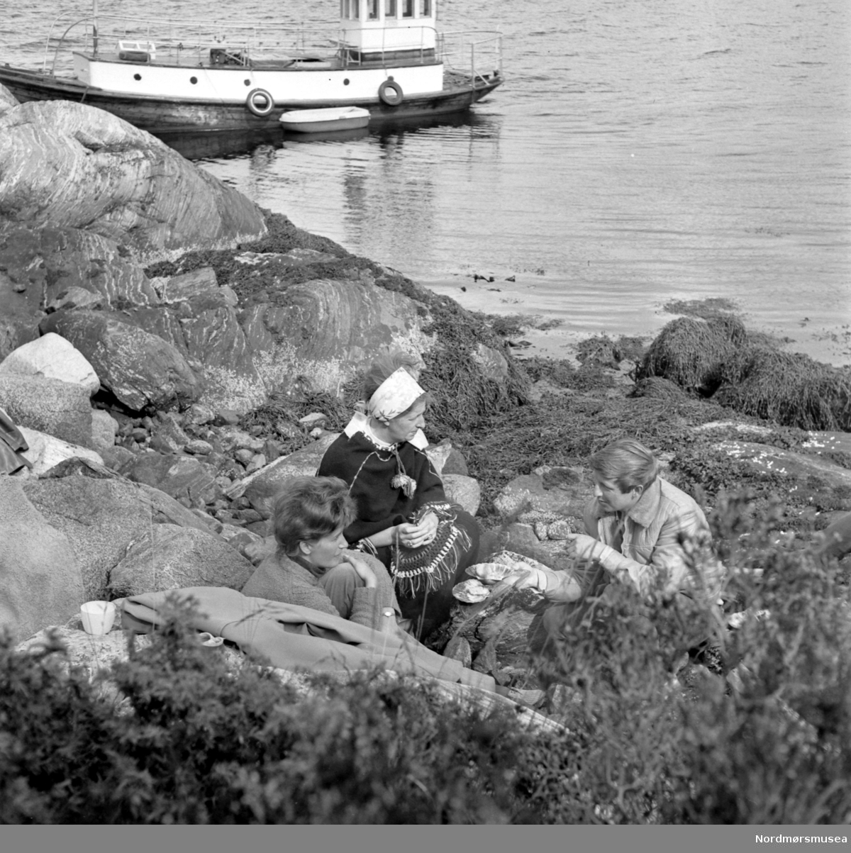 Fra en reportasje i Aftenposten om fiske mm. fra Vågen. Se brev 261/84, Arkiv nr. 44. Her ser vi under smakingen av de tilberedte skjellene. Bildet er i serie med 1984/31:1 (KMb-1984-031.0001.jpg), og som er datert juni 1971. Nordmøre Museum