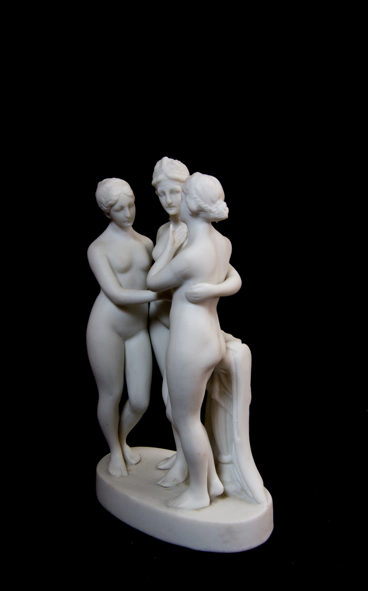 Studiemodell föreställande de tre gracerna i parian. De tre nakna kvinnorna i helfigur håller armarna om varandra. Bakom dem en draperad stubbe. Oval fotplatta.