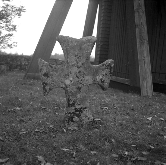 En korsformad gravsten, vid klockstapeln. Kyrkogården. Vittaryds kyrka.