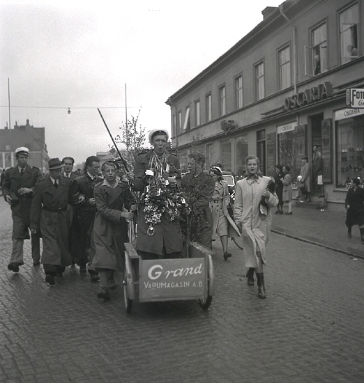 Andra dagens studenter, 1944.
En student körs iväg i en kärra längs Storgatan, från Stortorget. Till höger syns dåv. P.N. Perssons fastighet med  bl.a. Wigéns och skoaffären Oscaria.