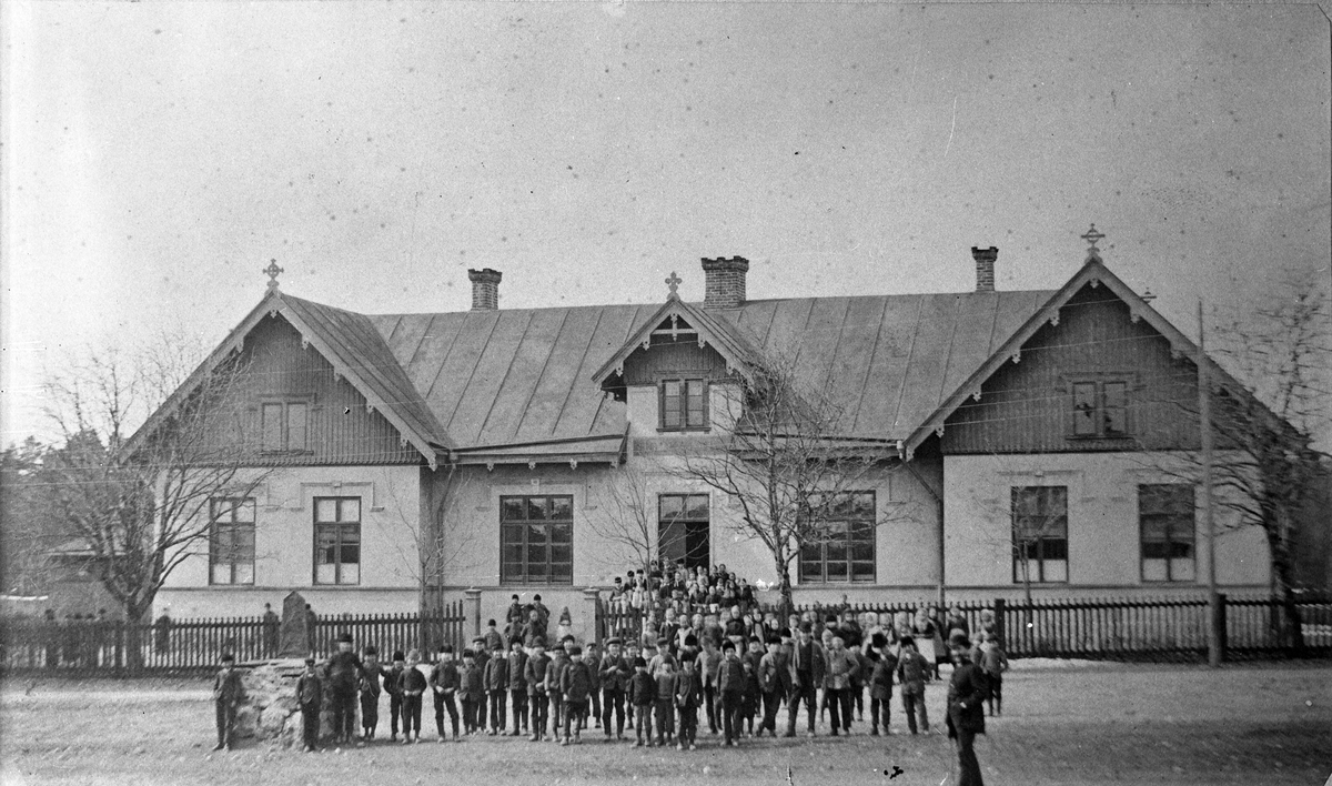 Strömsbro Folkskola exteriör med en grupp skolbarn framför. Fotografiet är tagit för ombyggnaden av skolan.