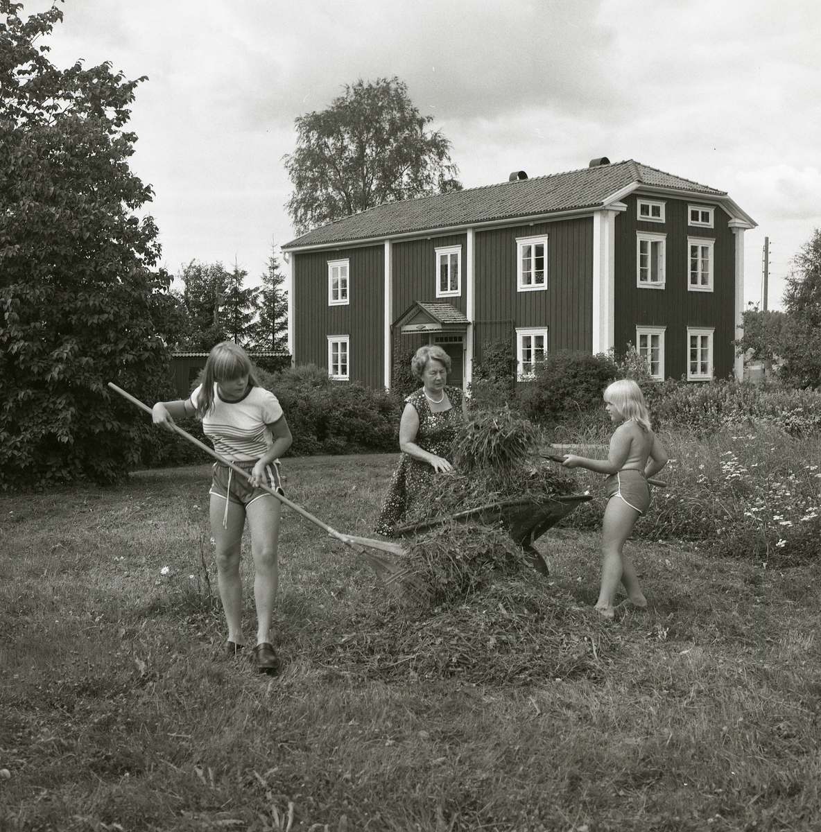 På gården Sunnanåker i Glösbo krattar en kvinna och två flickor gräs. Gräset placeras i en skottkärra parkerad mitt på ängen. Det är sommar 1981 och hela sällskapet är tunt klädda i short och klänning. Bostadshuset syns bakom de idogt arbetande, likaså den organiserade trädgården med buskar och träd.