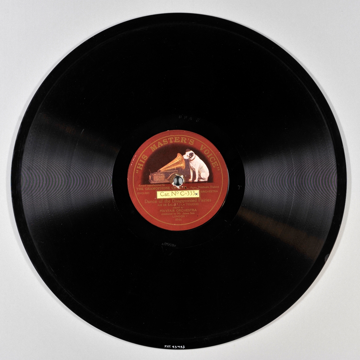 Svart plate med rød etikett med gullskrift og en hund som sitter og lytter til en grammofon.