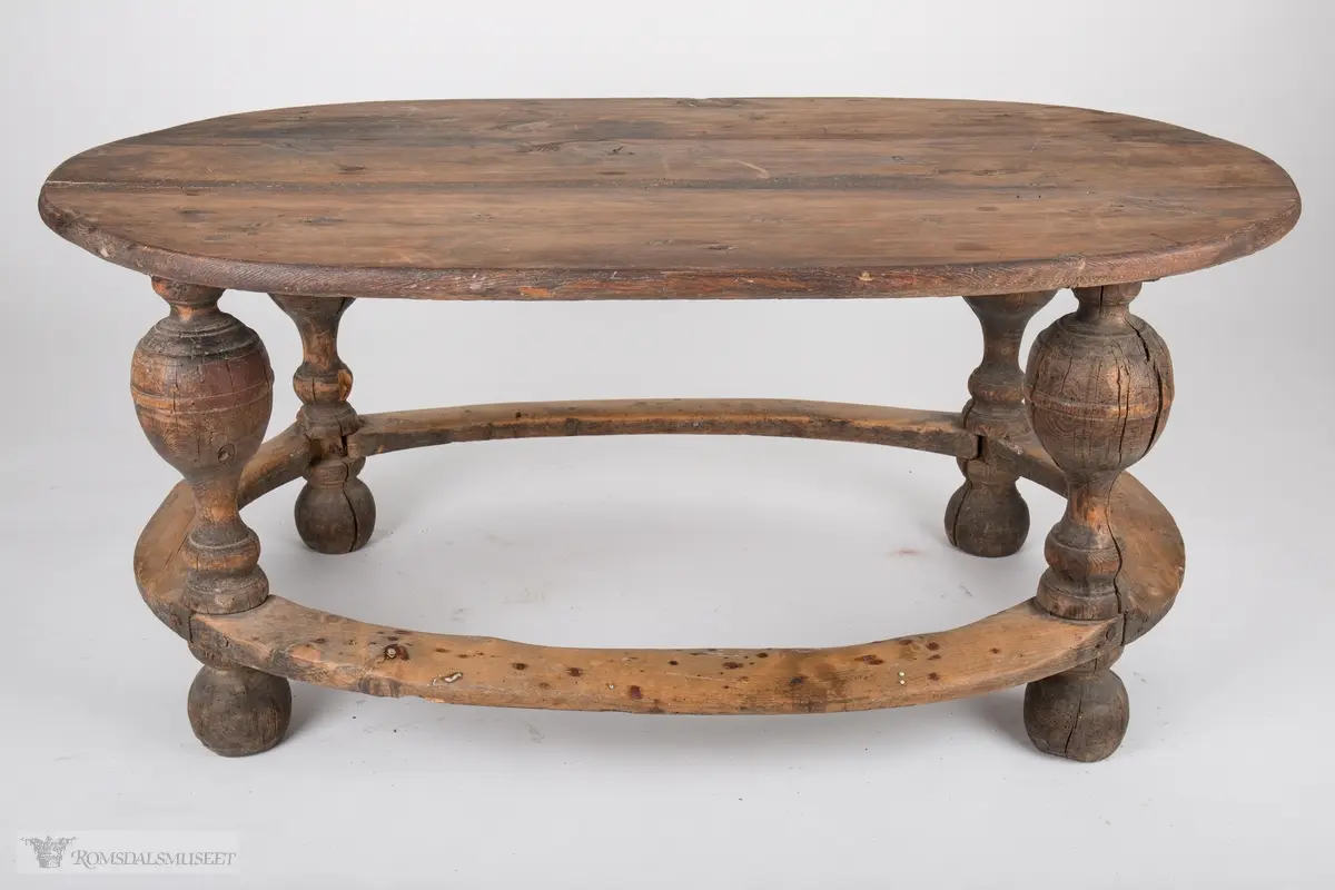 Ovalt trebord med balusterformede ben som har en sammenbindende sville som går rundt hele bordet. Rester etter brun maling.