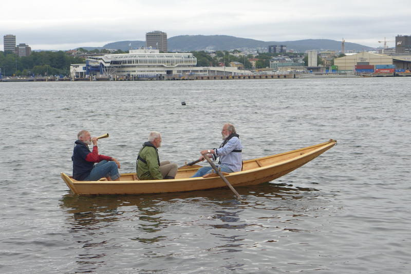 Tre menn ombord Holmsbuprammen, Oslo i bakgrunnen. (Foto/Photo)