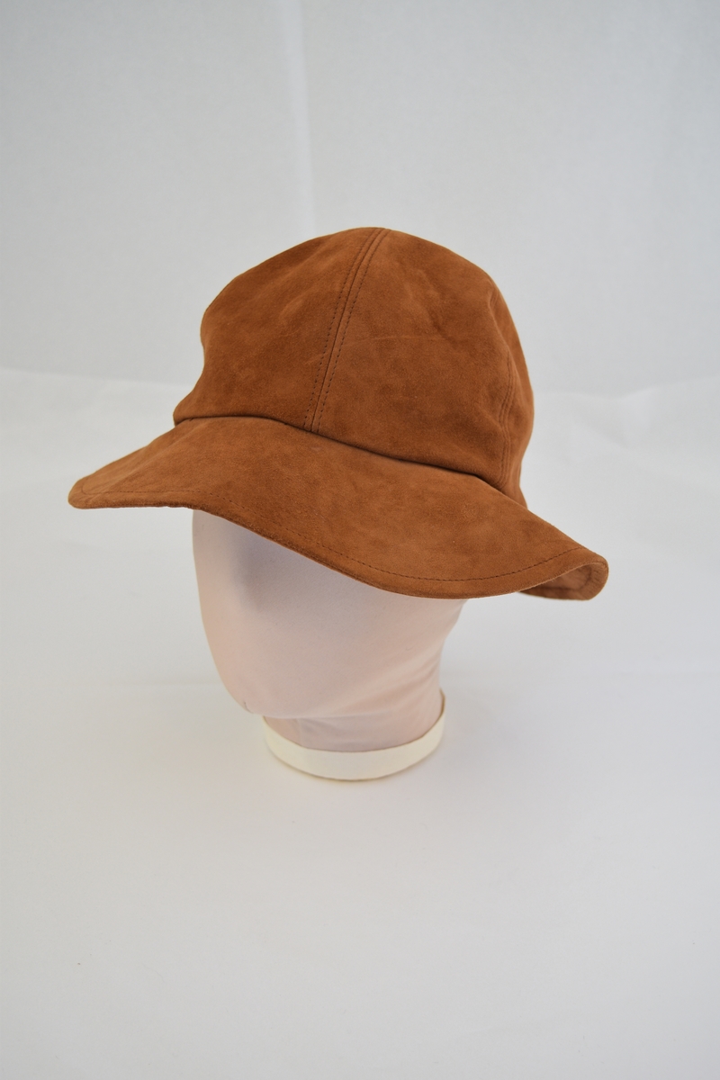 Hatt av semsket skinn.  Hatten er rund med brem, bremmen er noe smalere på hattens bakside. Hoveddelen består av seks trekantede stykker og bremmen består av et stykke. Foret med tynt hvitt stoff på innsiden.