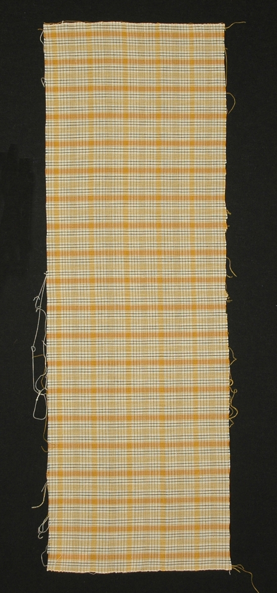 Bomullstyg, till klänning, 27 x 80 cm, tuskaft. Smårutigt i vitt, gult och svart.

Katalogiserad av Karin Nordenfelt, Elisabet Stavenow,
Marie-Louise Wulfcrona-Dagel.