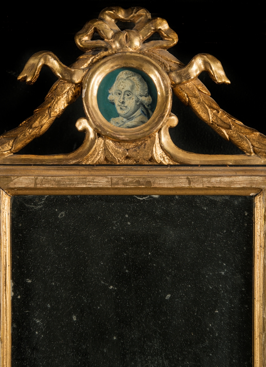 Tvådelad ram med spegel och en akvarell. Målningen bär texten "Amphion Cap:t Jonas Pettersson, Ancona 1795." Över spegeln sitter även ett litet runt mansporträtt i akvarell. Den förgyllda ramen är krönt med bladornament och en rosett med hängande ändar.