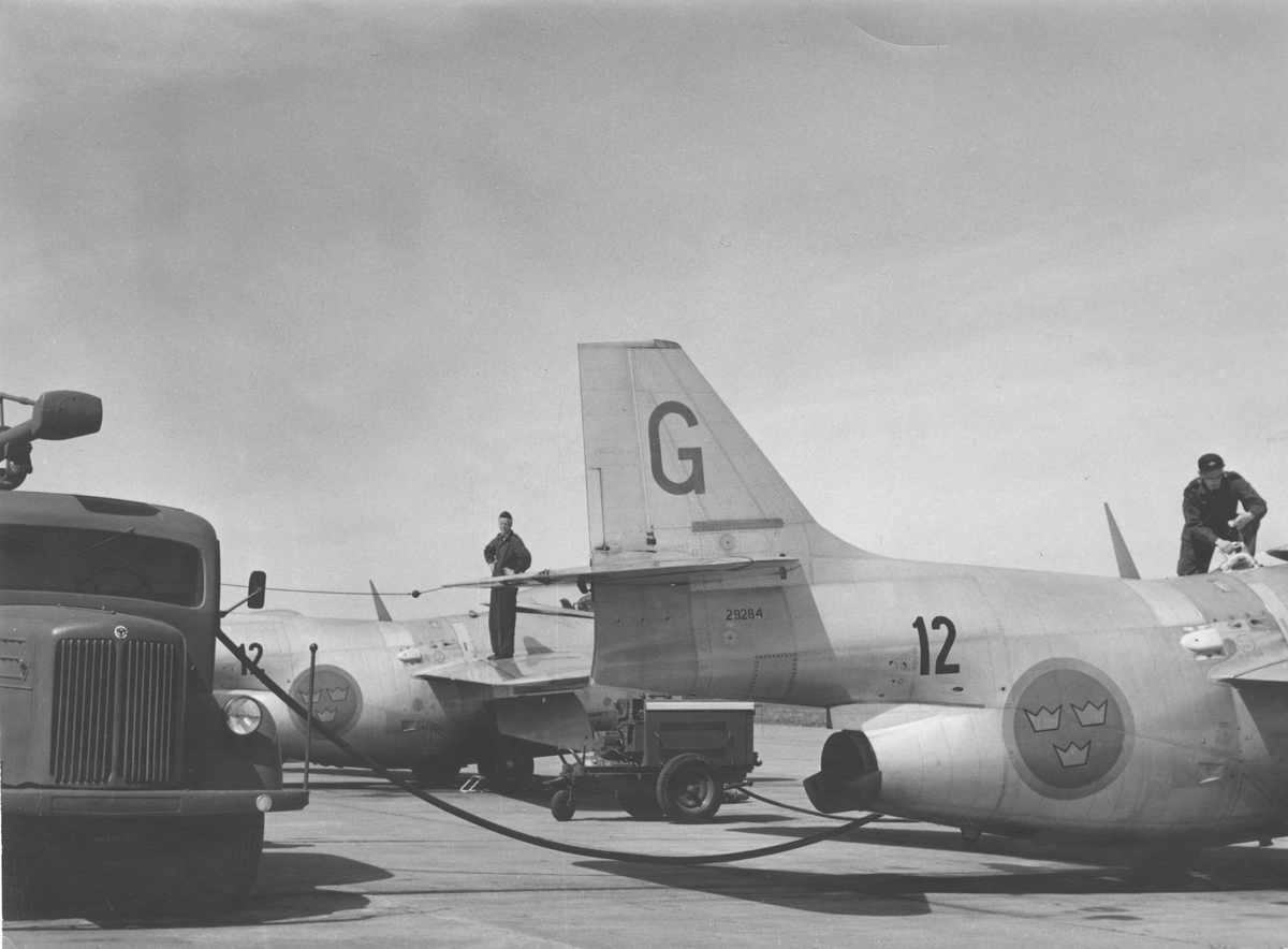 Tankning av flygfotogen i ryggåstank på flygplan J 29 tillhörande F 12 Kalmar. Närmast flygplan nummer 29 284. I bakgrunden syns en startvagn.