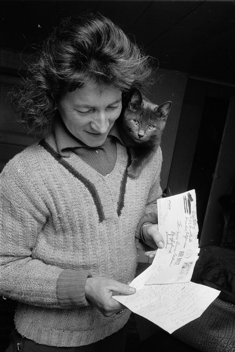 Clary Huldt med katt på axeln läser brev, Riala, april 1967