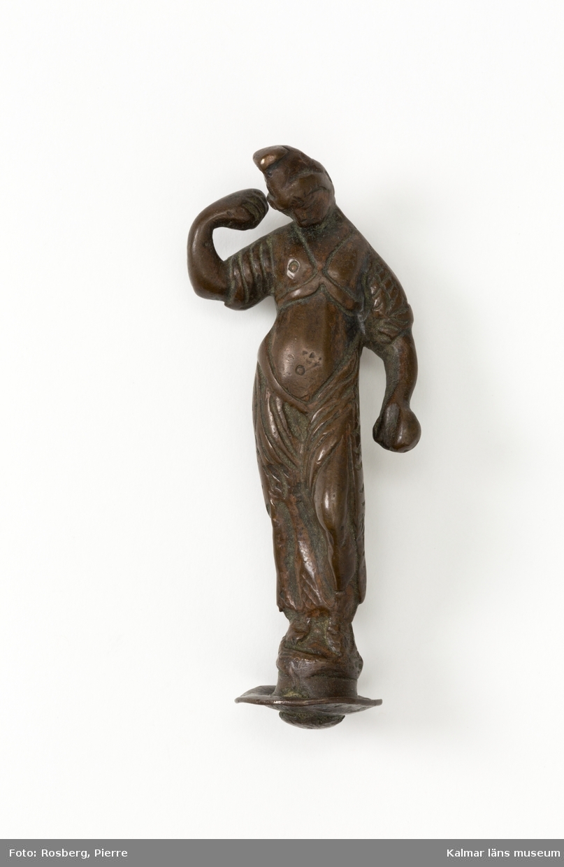 KLM 4024. Statyett, av brons. Dansande flicka i fryzisk mössa. Högra handen upplyftad. Kan eventuellt vara ett reflexornament på ljuskrona. Datering, 1600-tal.