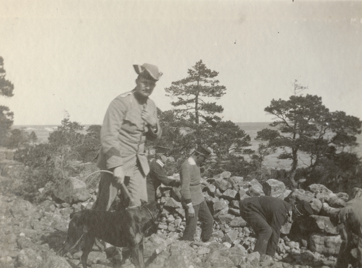 Officerare från Göta livgarde med sin hund. I bakgrunden soldater i befästningsarbete.