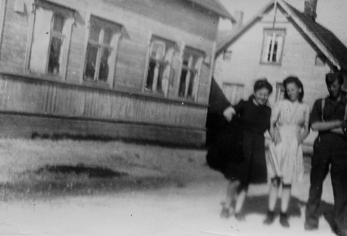 To jenter og en ung mann avbildet i gate i Vadsø. Flere trebygde bolighus i bakgrunnen.
