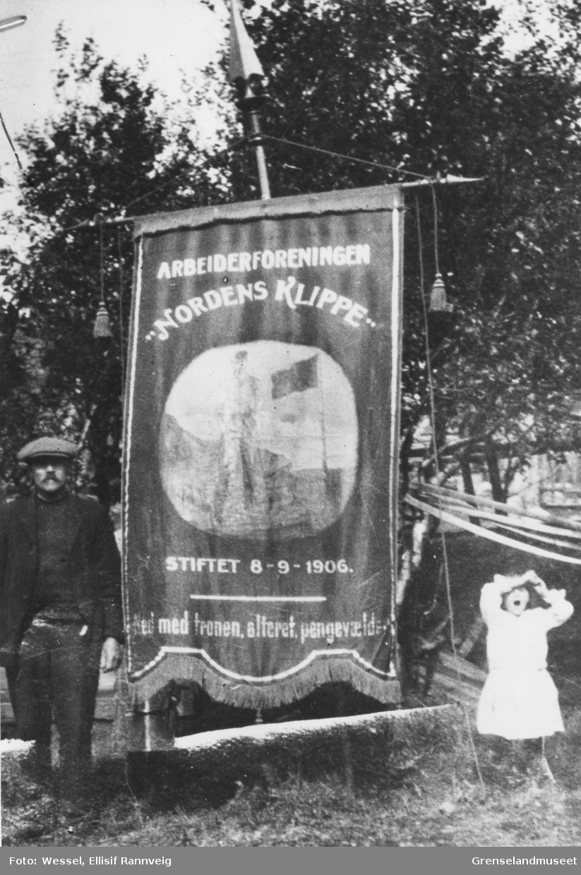 Arbeiderforeningen Nordens Klippes fane fra 1907 med påskriften: Ned med tronen, alteret, pengevældet. Per Matson Nylander - foreningens tredje leder - til venstre.