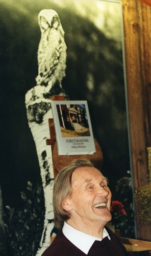 Fotografiet är taget i samband med utgivningen av boken "Förstukvistar i Hälsingland", 1995. En skrattande Hilding står framför sin bok. På väggen bakom ser man en uppförstorad bild av en uggla.