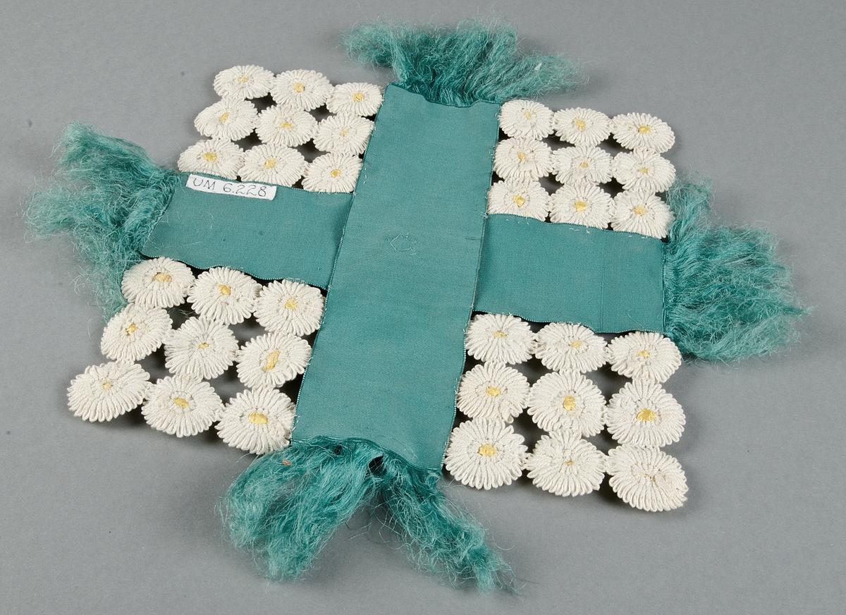 Piedestalsduk av turkosa sidenduschessband och blommor av vita bomullsband med knappar klädda med gult siden.

