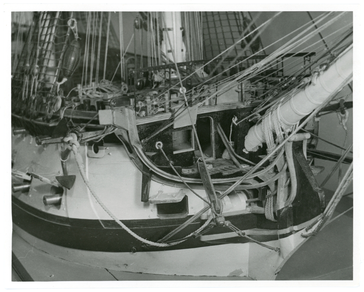 Detaljfoto av förskeppet från modellen av linjeskeppet Kronprins Gustaf Adolf. Man ser övre delen av förskeppet från vänster förifrån med bogspröt, öppna styckporter, ankaren och undere delen av fockmast och stormast.