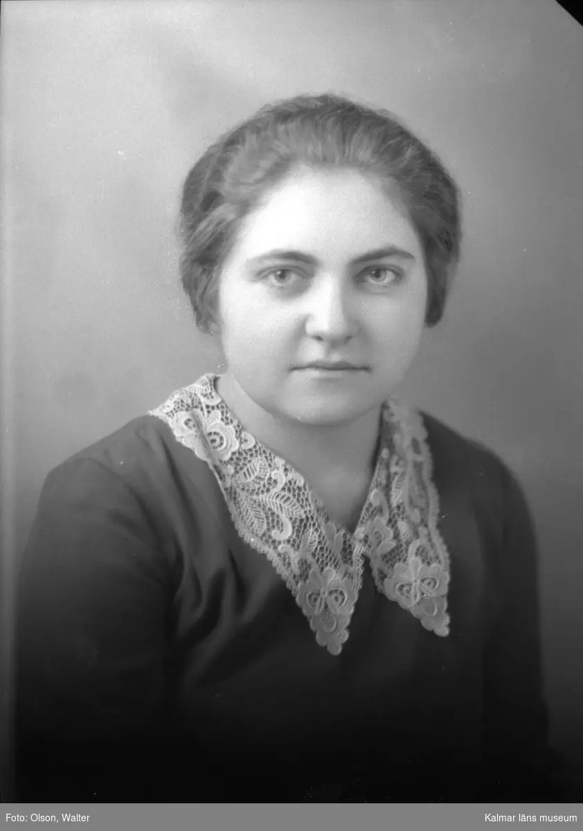Ateljébild på en kvinna i jumper och spetskrage. Enligt Walter Olsons journal är bilden beställd av fröken Ingeborg Nilsson.