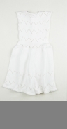 En vit ärmlös mönsterstickad klänning som knäpps med tre stycken knappar på vardera axel. Klänningen har en virkad uddformad dekorkant som löper runt ärmhålen.
