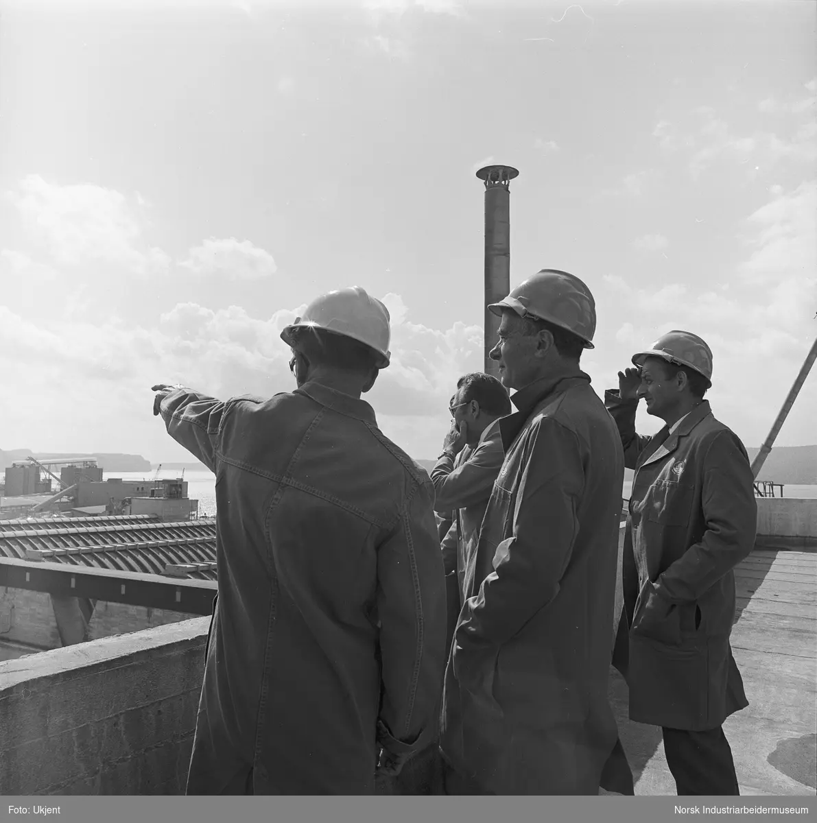 Tre menn ser utover fabrikkområdet på Herøya.