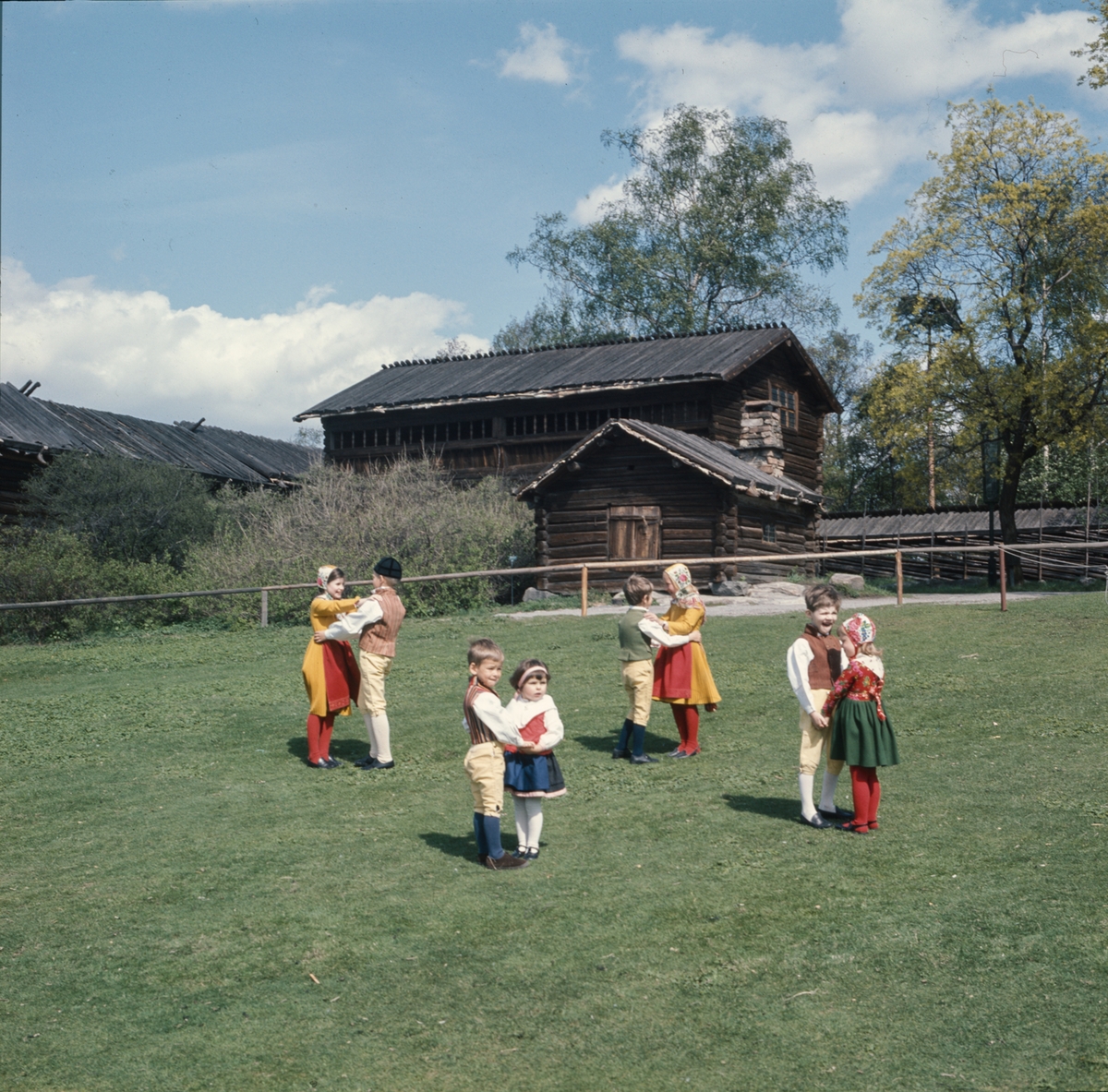 Dansande barn på Orsakullens gräsmatta iklädda folkdräkt.