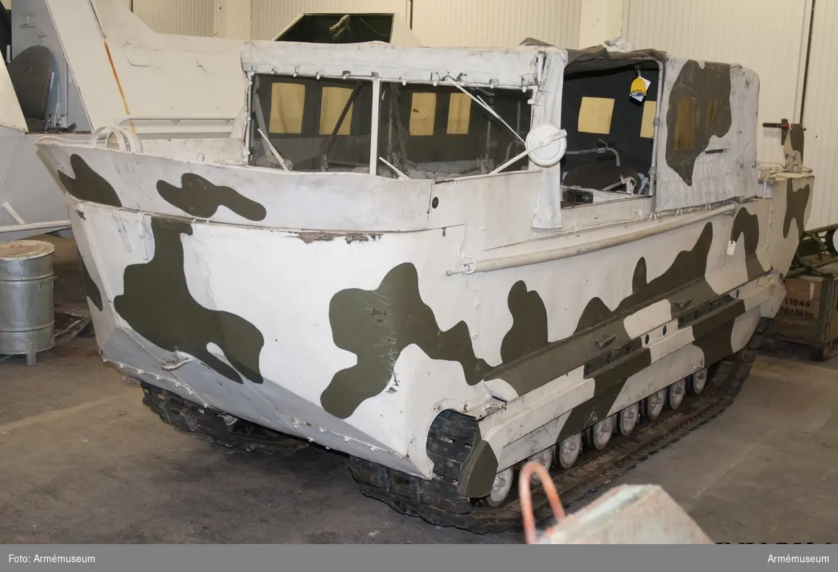 Med flyttankar. Amerikansk beteckning M-29 C. Bandvagnen har tillhört Distriktskommando Tröndelag Norge (se instruktionsbok för WEASEL (Snöbeltevogn M-29 og M-29 C) 1950 (A 110) och Bandvagn m/48).

I vänster fack i fören finns följande tillbehör: 
- låda för kulspruteband, grönmålad av aluminiumplåt för tysk kulspruta MG 34 (jmf AM.004701), men här använd som tillbehörslåda med följande innehåll: 
- generatorrem Optimat 17 made in Germany; 
- fläktrem 3030-517-1134 Belt BA RD-A 860; 
- 2 st tändstift "Blue Crown Husky M-7";
- plåtlåda med skumgummiinredning med 3 st lampor och 2 st säkringar; 
- järntråd;
- 5 st plugg för skrov 3/4" av järn, märkta: fyrkant, S,T,G ring m prick i; - plugg av mässing;
- 12 st saxsprintar i brunt kuvert märkt: 42-P-5347 Splinter ass;
- 4 st träkilar med kedja emellan 2 och de andra två löpande lösa på kedjan; 
- 2 st kedjor med vardera fyra lösa ändar med vinkelhöjda (90 grader) krokar okänd användning, 
- hänglås utan nycklar.

Lösa tillbehör i facket: 
- länspump med slang; 
- domkraft märkt: Drednaut 961 made in USA, med vev; 
- domkraftsfäste för bandspänning (nya typen);
- domkraftsfäste för boggi märkt 41-L-1392;
- domkraftsfäste för boggi märkt 41-L-392 (vinklat järn).

I passagerarutrymmet: Bakom vänstra stolen på sidan en strålkastare (kan fästas på vagnens utsida) märkt: stort C med litet c i, 107406G, på underkant av glaset står BW i mitten av glaset GE (troligen General Electric); 
- 2 st vinkeljärn som passar i hålen på passagerarutrymmets främre vägg, troligen radioanläggning. 

En vit båtshake hänger på vänstra utsidan av vagnen.