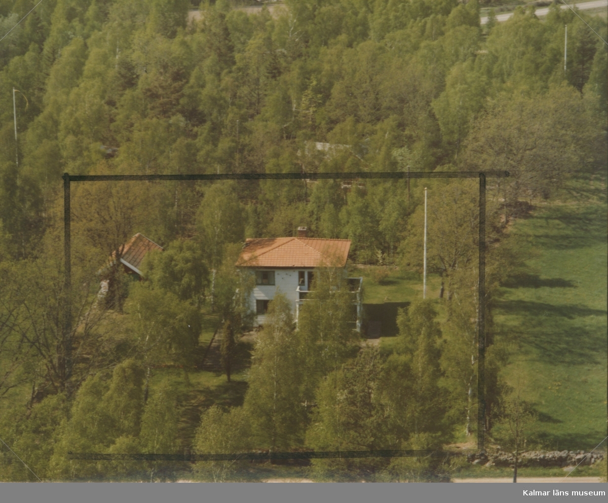 Flygfoto över Ålem. Enfamiljshus med valmat tak sidobyggnad och träd. Bild två enligt markeringen.