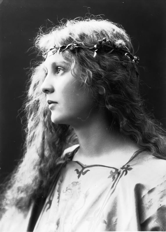 Studioportrett av kvinne i kostyme og utslått hår - overdel med riksvåpen og blomsterkrans i håret. 1908. (Foto/Photo)