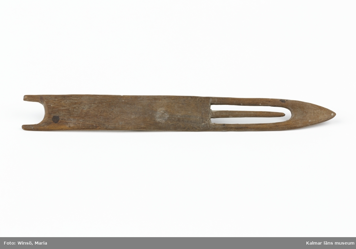 KLM 5938. Nätnål, trädnål. Användes för tillverkning av fiskenät. Av trä med snidade detaljer. Vanlig form.