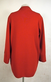 Röd maskinstickad kofta av ullgarn med tillhörande kjol ( 106259:2).
 Knappar av mässing med firmamärket "Busnel".
Har tidigare tillhört dottern Elisabeth (givaren)
