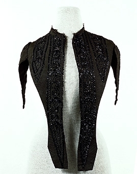 Del av klädningsliv sytt av svart ripsvävt siden, dekorerat med bårder av svarta pärlbroderier. Troligen är pärlorna av glas.