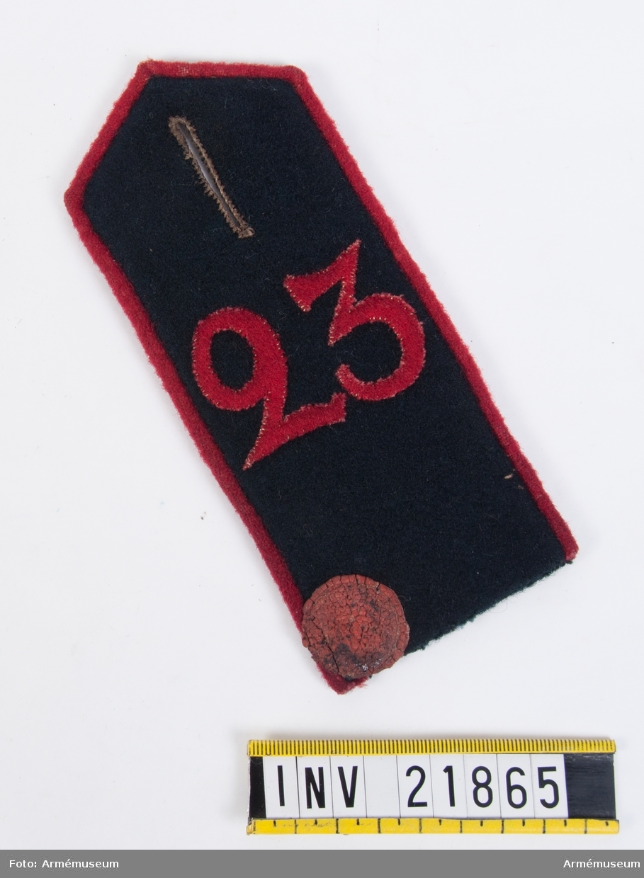 Grupp I.
Axelklaff av svart kläde med röd passpoal och siffran "23" i rött kläde.