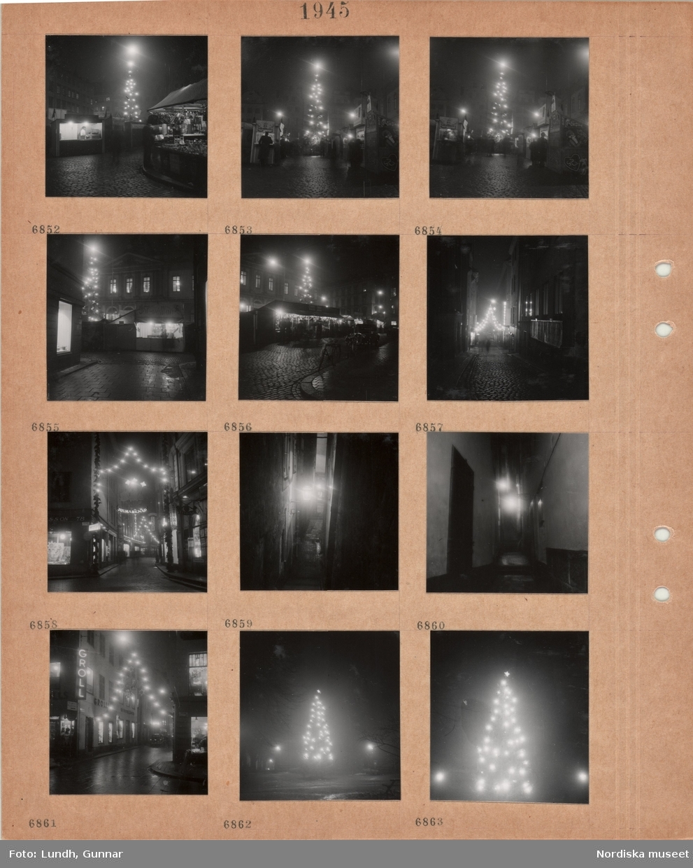 Motiv: Stockholm, Stortorgets julmarknad, salustånd, hög julgran med tänd belysning, stenlagd gata med tända juldekorationer, butiksfönster och skyltar, smal gränd med tänd vägglykta, julgran med tänd belysning.