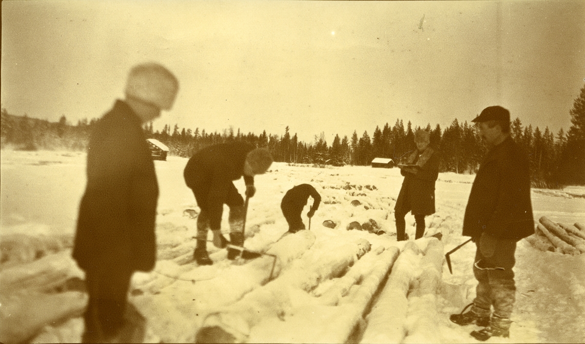 5 menn på merking ved Storneset, vestre Grøna (om vinteren). To løer i bakgrunnen.
Til høyre: Gustav Galaasen, Jons (26/3 1876 - 1940)