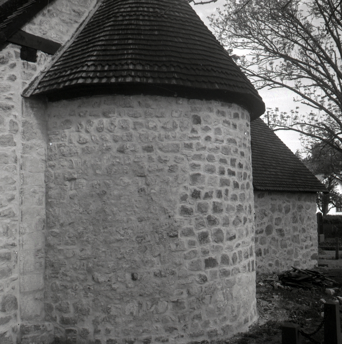 En stenvägg och ett halvt torntak på Hossmo Kyrka.