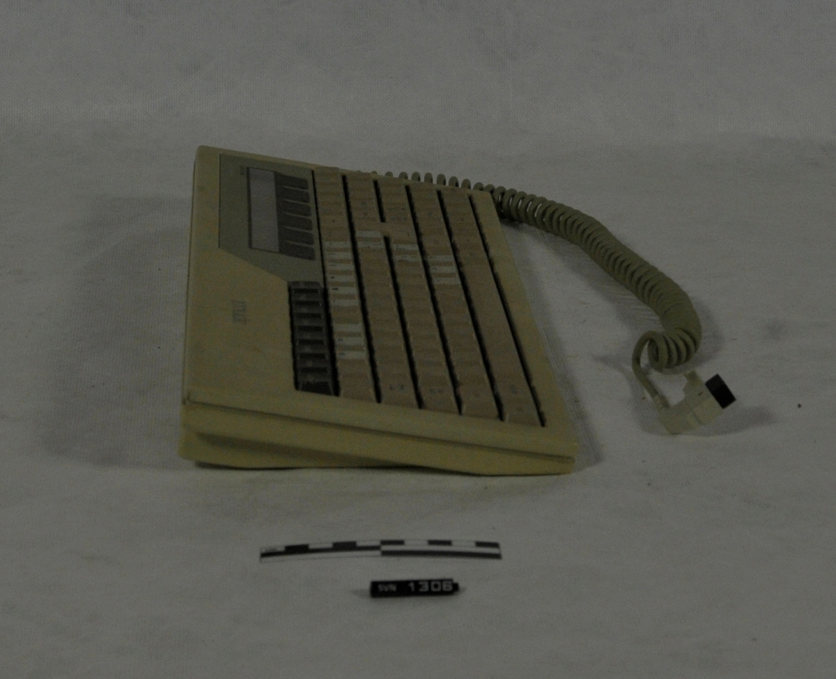 Datamaskinen består av kabinett (A), skjerm (B) og tastatur (C).
Datamaskinen er gul/meget lys brun.
I kabinettet er det to diskettstasjoner. Det var diskett i begge.