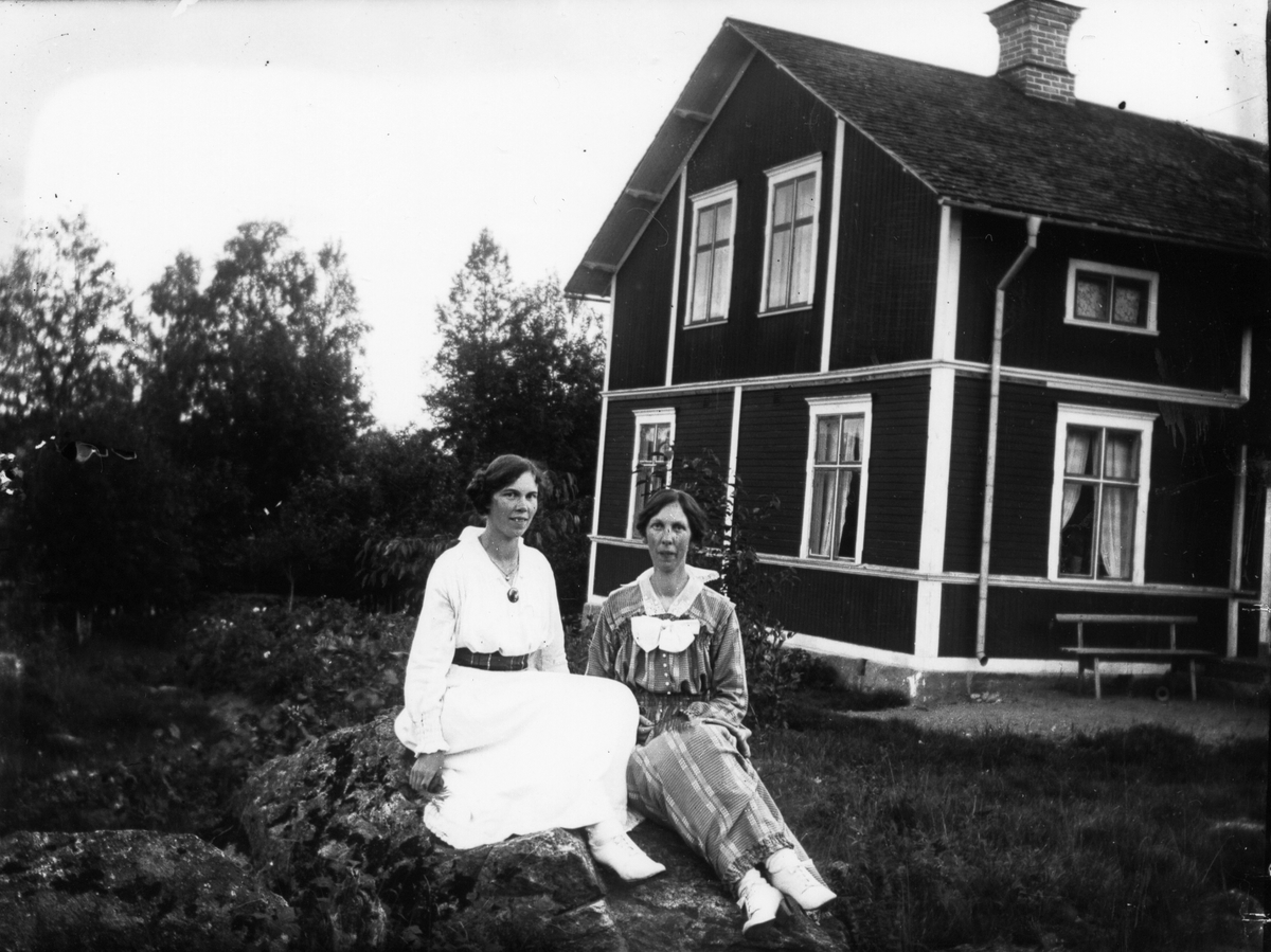Två kvinnor framför husknut.