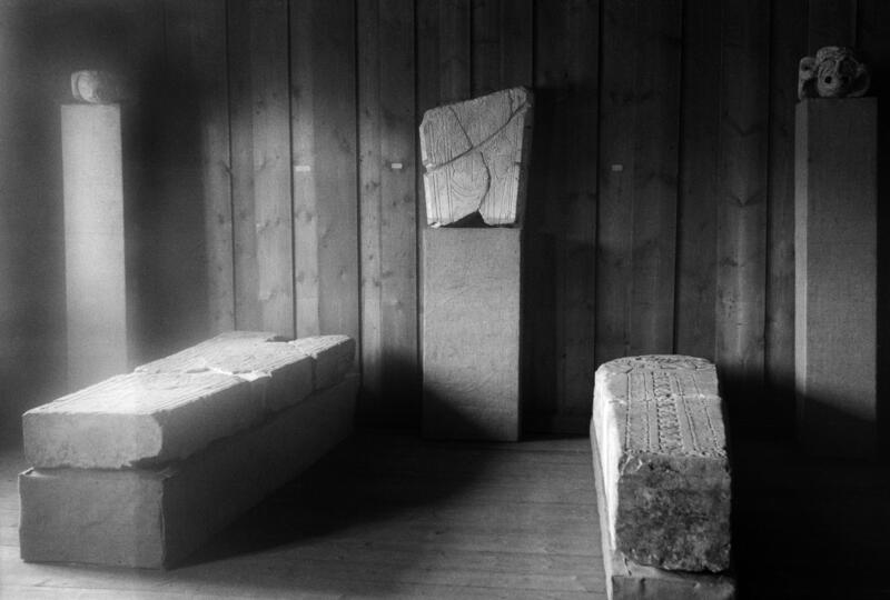 Gravsteiner fra middelalderen ligger på utstilling i et gammelt tømmerhus.